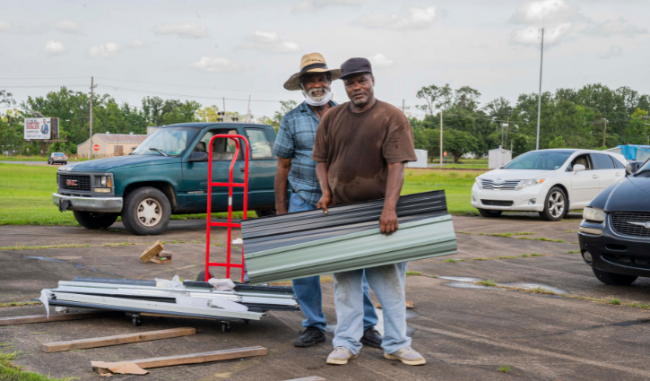 Pastor Harris of the Evergreen Missionary Baptist Church in DeQuincy, Louisiana and a volunteer help construct a shed during a bottled water and gift card giveaway to local residents still affected last year’s Hurricane Laura and Hurricane Delta.