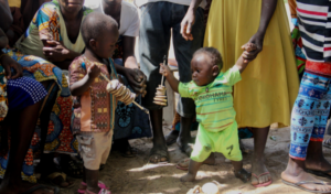 Two children playing, surrounded by community members and Episcopal Relief & Development program participants. 