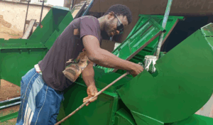 Jerry gives a freshly fabricated maize thresher its protective green finish.