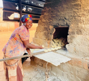 Elsa placing the dough into the stone oven.